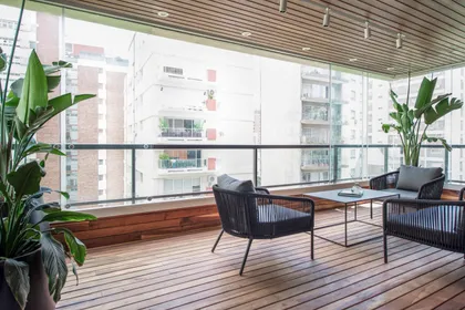 Balcón moderno con muebles de ratán y vista urbana — proyecto Depto Teodoro Garcia, por Ayelen Mayer Arquitectura, en Buenos Aires